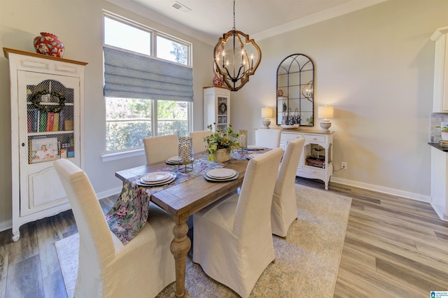 dining area with baseboards, a notable chandelier, visible vents, and light wood-style floors