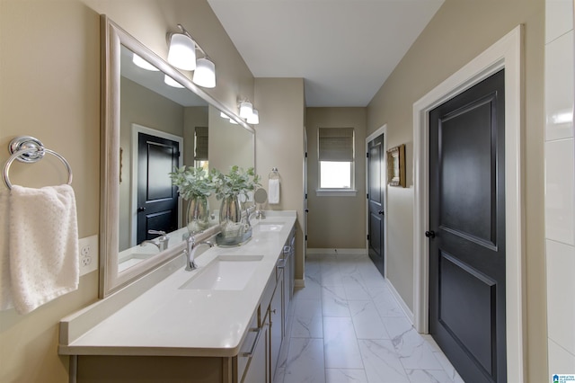 bathroom featuring marble finish floor, a sink, baseboards, and double vanity