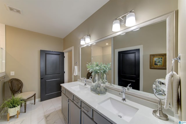 bathroom with marble finish floor, visible vents, a sink, and double vanity