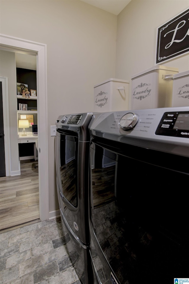 clothes washing area with laundry area, stone finish flooring, baseboards, and separate washer and dryer