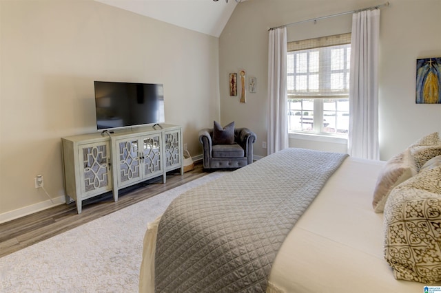 bedroom with lofted ceiling, wood finished floors, and baseboards