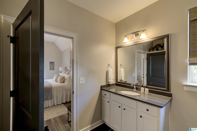 bathroom with baseboards, wood finished floors, ensuite bathroom, vaulted ceiling, and vanity