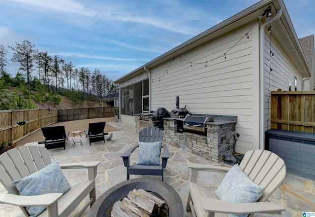 view of patio / terrace featuring an outdoor kitchen, a fenced backyard, a fire pit, a grill, and a sunroom