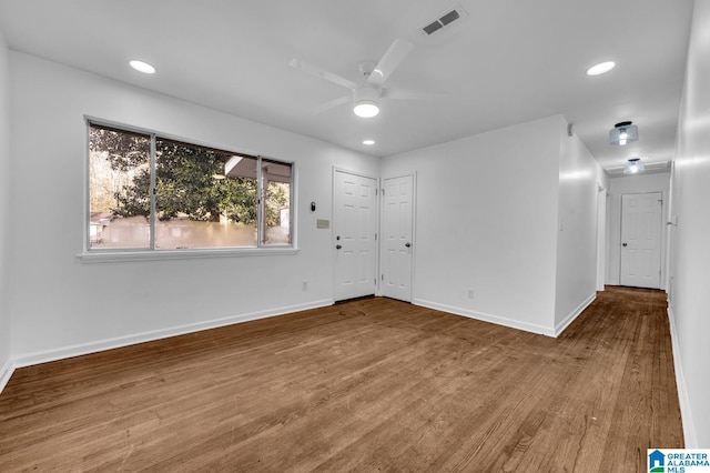 unfurnished room featuring a ceiling fan, baseboards, visible vents, and wood finished floors