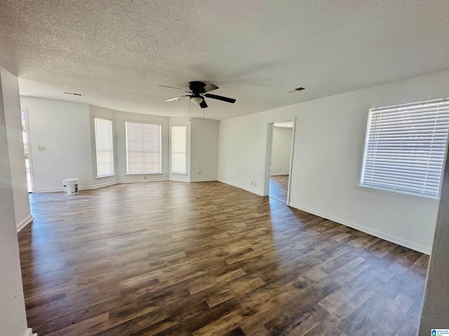 unfurnished living room with ceiling fan, a textured ceiling, dark wood-style flooring, visible vents, and baseboards