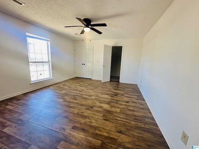 unfurnished bedroom with visible vents, baseboards, a ceiling fan, dark wood finished floors, and a textured ceiling