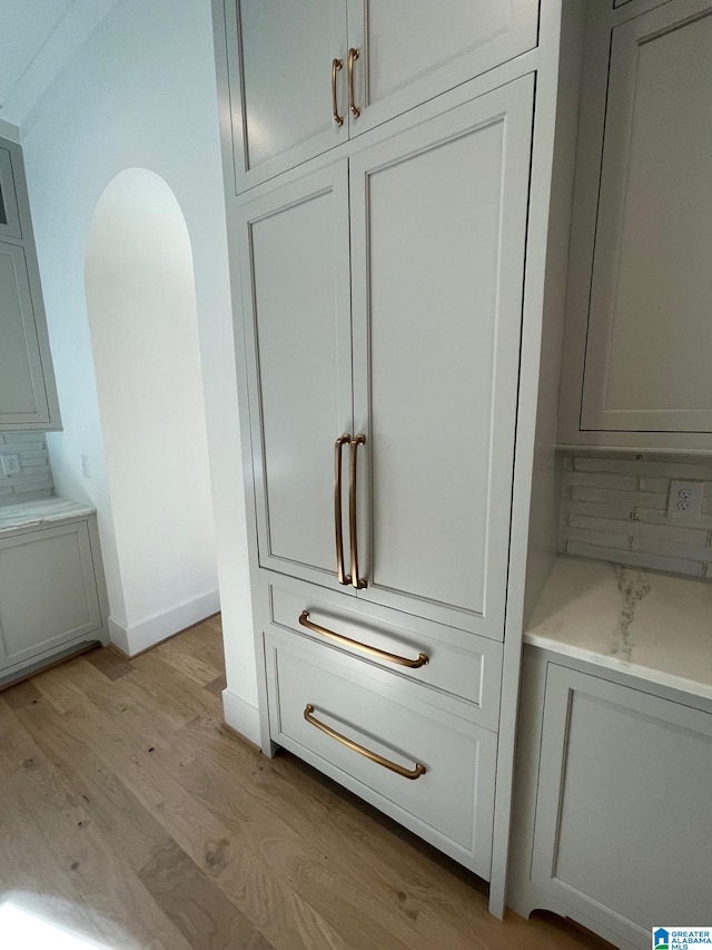 interior details with washer / dryer, baseboards, arched walkways, and wood finished floors