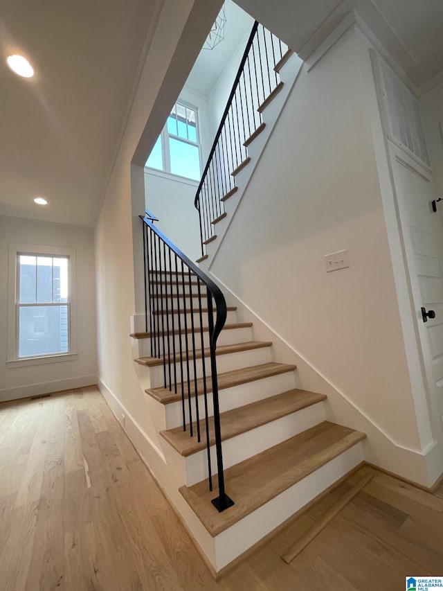 stairway featuring plenty of natural light, wood finished floors, and baseboards