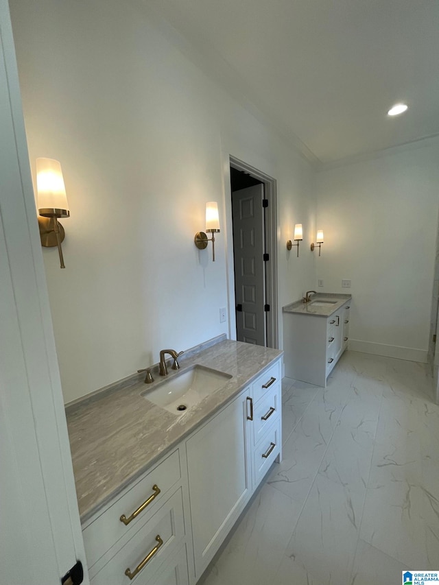 bathroom with marble finish floor, two vanities, a sink, and baseboards