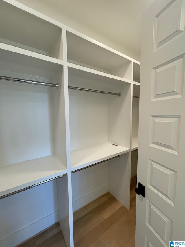 walk in closet featuring built in study area and wood finished floors