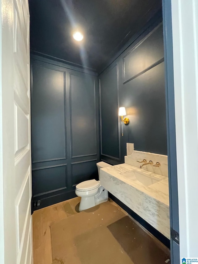 half bath featuring toilet, a decorative wall, and a sink