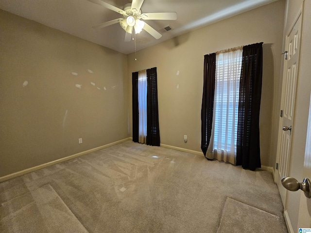 empty room with carpet flooring, visible vents, ceiling fan, and baseboards