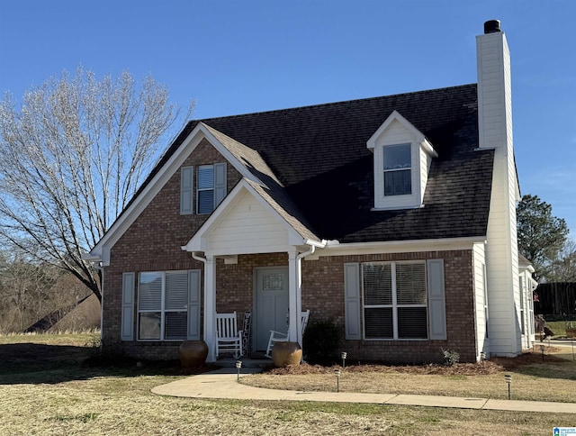 view of front of house with a front yard, a chimney, and brick siding