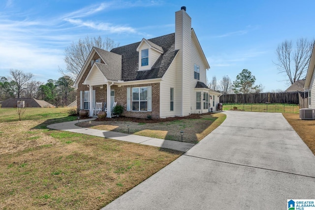 view of front facade with central AC, brick siding, a front yard, and a shingled roof