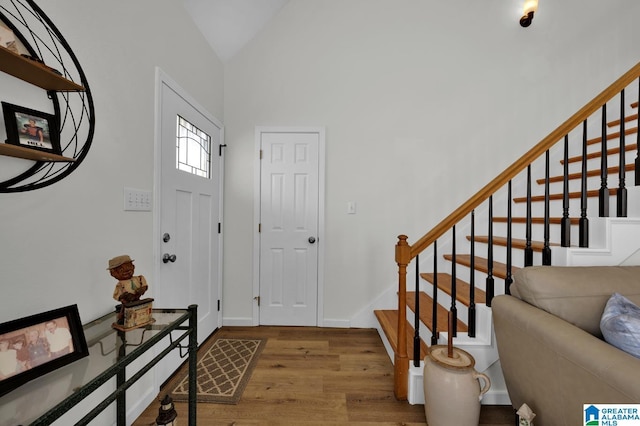 entryway with lofted ceiling, baseboards, stairway, and wood finished floors