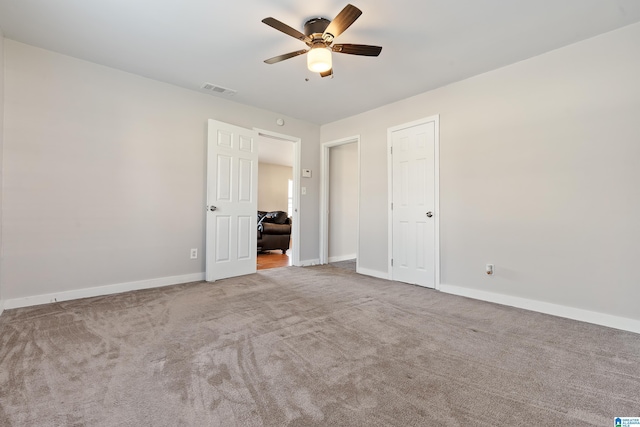 unfurnished bedroom with baseboards, carpet floors, visible vents, and a ceiling fan