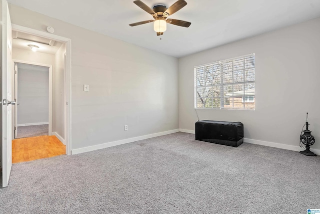 carpeted empty room featuring a ceiling fan and baseboards