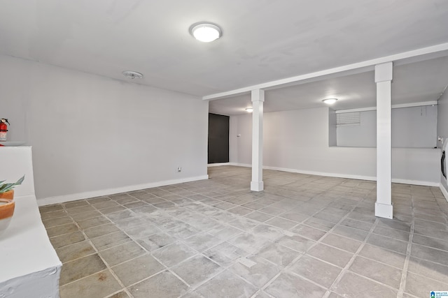 finished below grade area featuring light tile patterned floors and baseboards