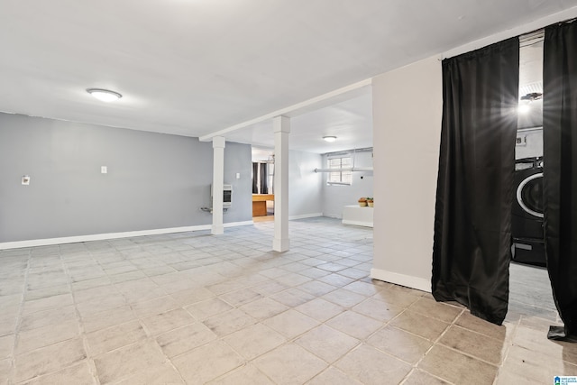 basement featuring heating unit, stacked washer / drying machine, and baseboards