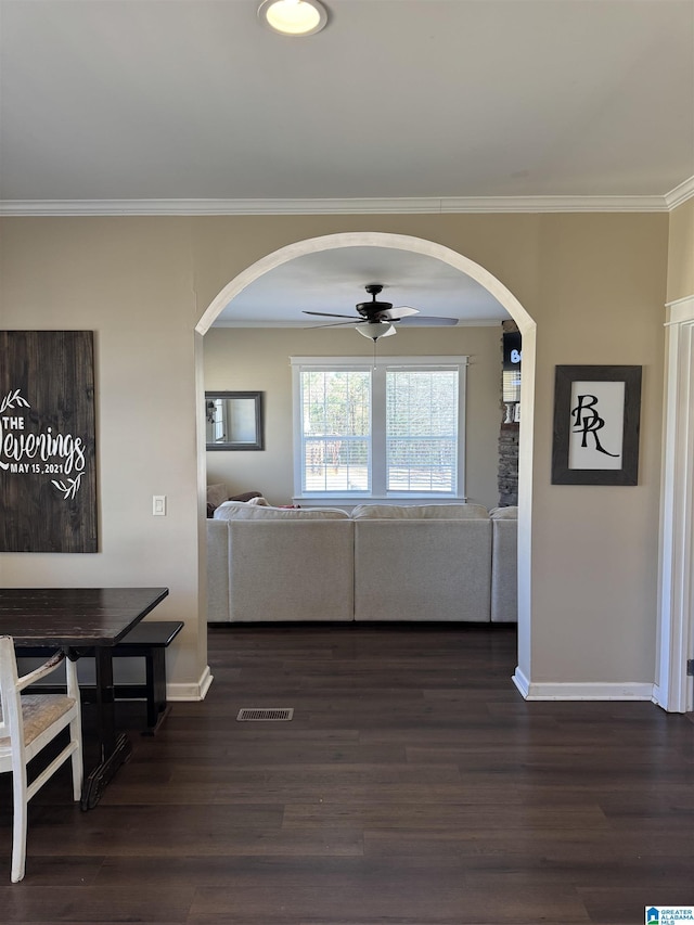 living room with ornamental molding, arched walkways, dark wood finished floors, and baseboards