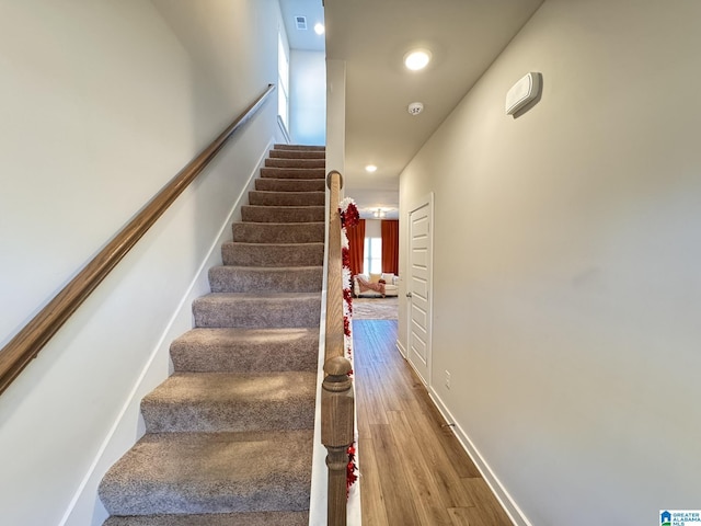 stairway featuring baseboards, visible vents, wood finished floors, and recessed lighting