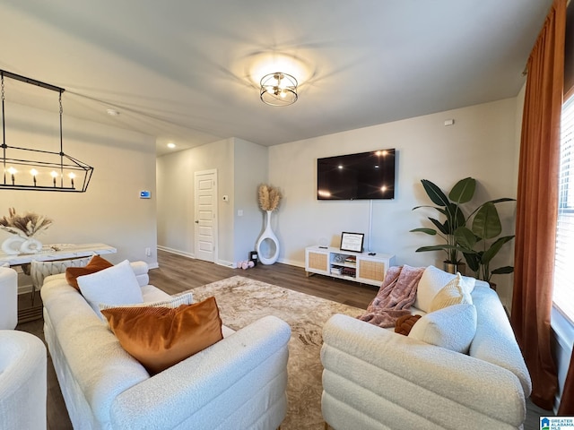 living room with a notable chandelier, baseboards, and wood finished floors