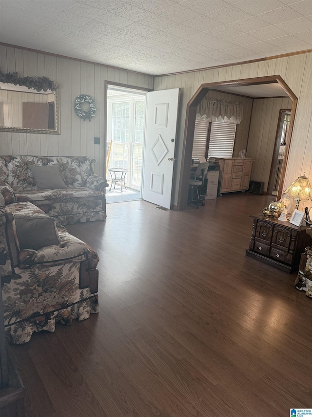 living room with arched walkways, wood finished floors, and ornamental molding