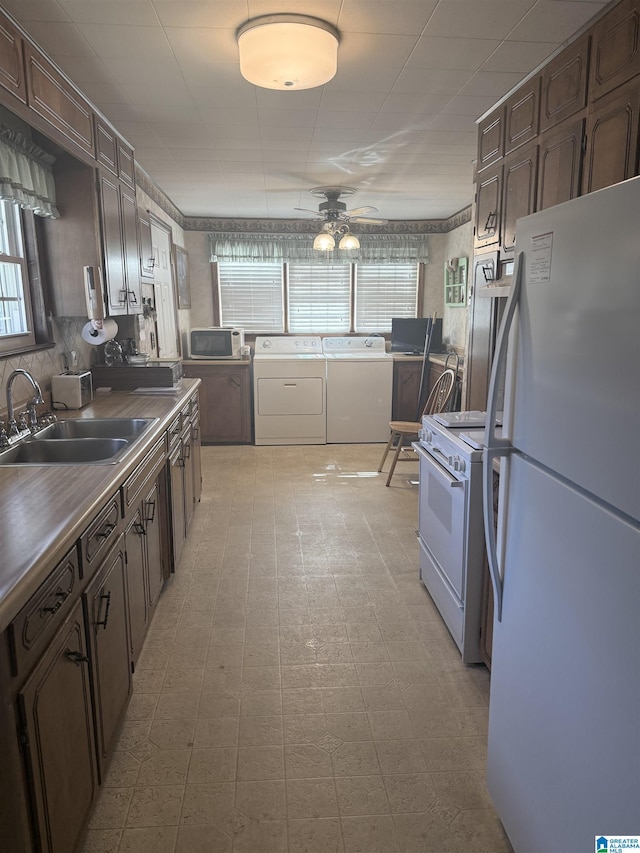 kitchen featuring light floors, a ceiling fan, a sink, separate washer and dryer, and white appliances