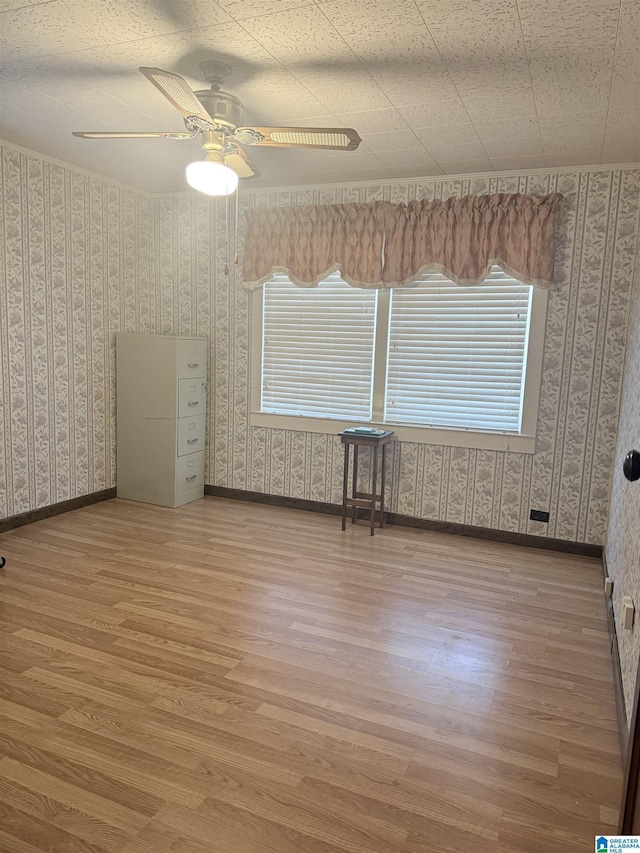 spare room with a ceiling fan, wood finished floors, baseboards, and wallpapered walls