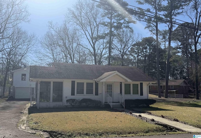 view of front of property featuring a garage, driveway, a shingled roof, and a front yard