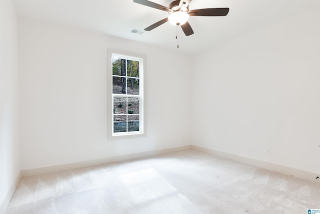 empty room featuring light carpet, ceiling fan, visible vents, and baseboards