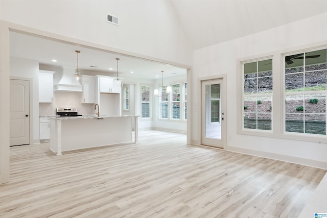 kitchen featuring light countertops, visible vents, open floor plan, a sink, and an island with sink