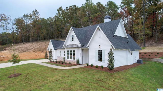 view of front of house with central AC, a front lawn, and a shingled roof