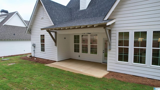 rear view of house featuring a yard, a shingled roof, ceiling fan, and a patio