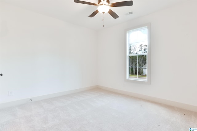 empty room featuring a ceiling fan, light carpet, visible vents, and baseboards