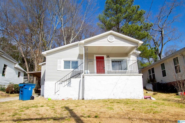 view of front of property with covered porch, a front yard, and stairs