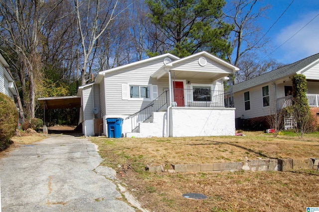 view of front facade featuring a carport, covered porch, driveway, and a front lawn