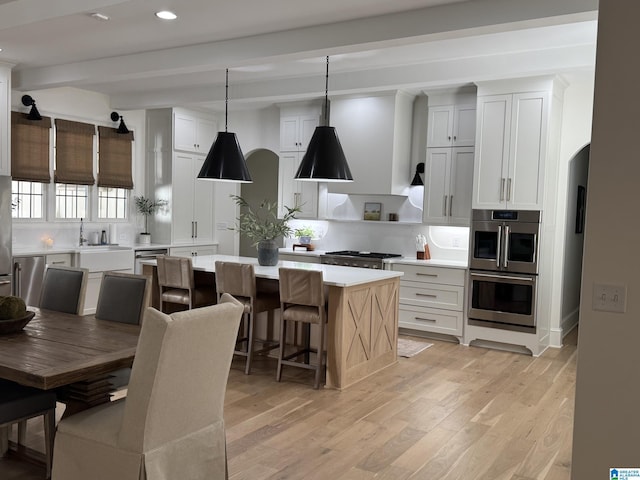 kitchen featuring a kitchen island, light wood-type flooring, light countertops, and beamed ceiling