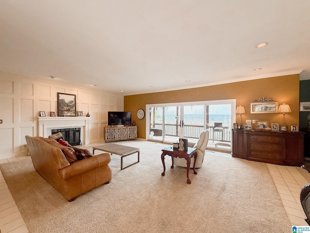 living area featuring crown molding, recessed lighting, light colored carpet, a decorative wall, and a glass covered fireplace