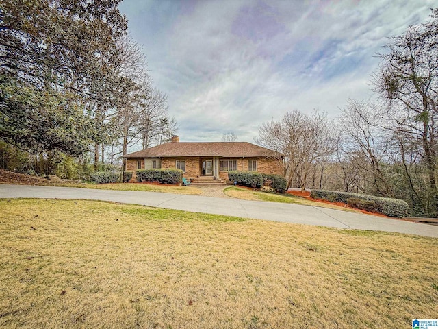 ranch-style house featuring brick siding, a chimney, and a front yard