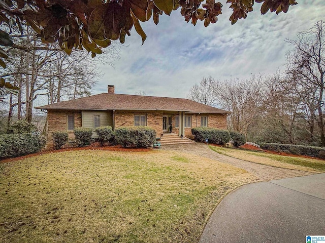 ranch-style house with brick siding, a chimney, and a front yard