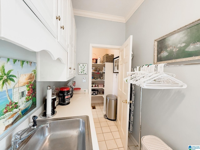 kitchen featuring light tile patterned floors, ornamental molding, a sink, and white cabinets