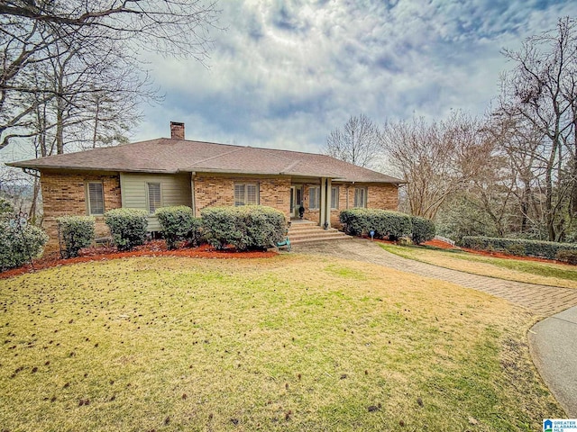 ranch-style home featuring brick siding, a chimney, and a front lawn