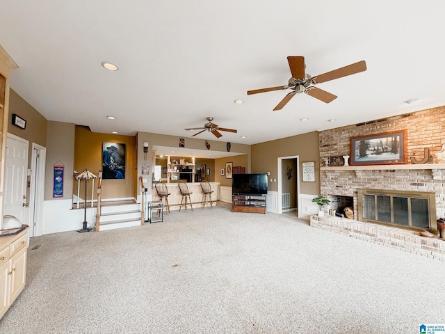 carpeted living area with a brick fireplace, stairs, visible vents, and recessed lighting