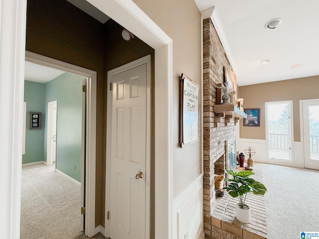 hallway with carpet floors, a decorative wall, and wainscoting