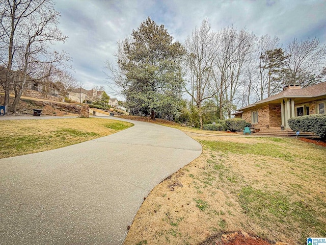 view of property's community with driveway and a lawn