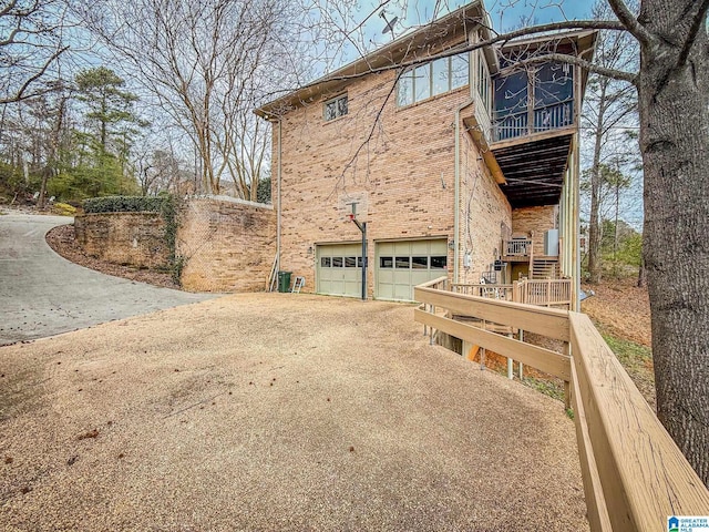 view of property exterior with a garage, driveway, and brick siding