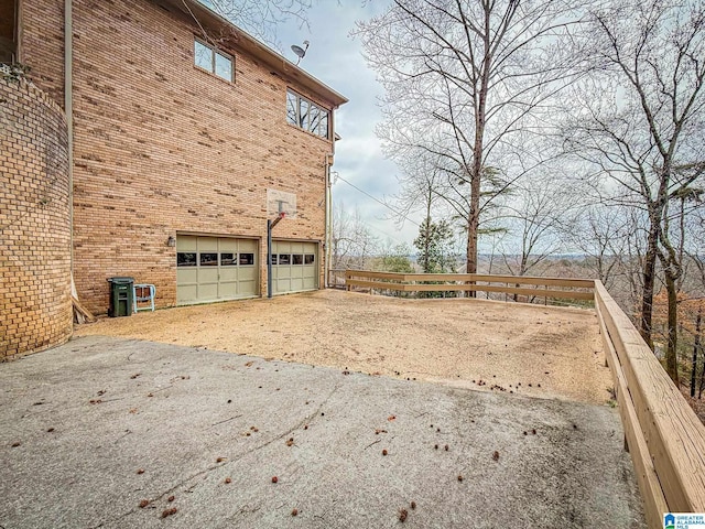 view of yard featuring a garage, concrete driveway, and fence