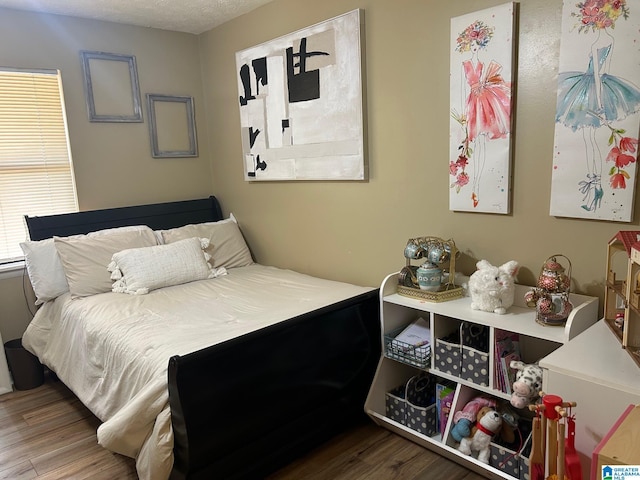 bedroom featuring wood finished floors and a textured ceiling