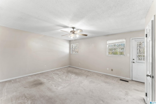 carpeted spare room featuring a textured ceiling, a ceiling fan, visible vents, and baseboards